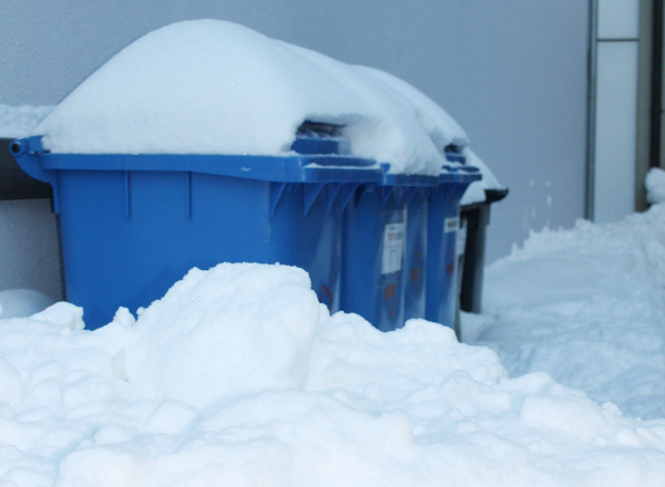 Mülltonnen stehen im hohen Schnee