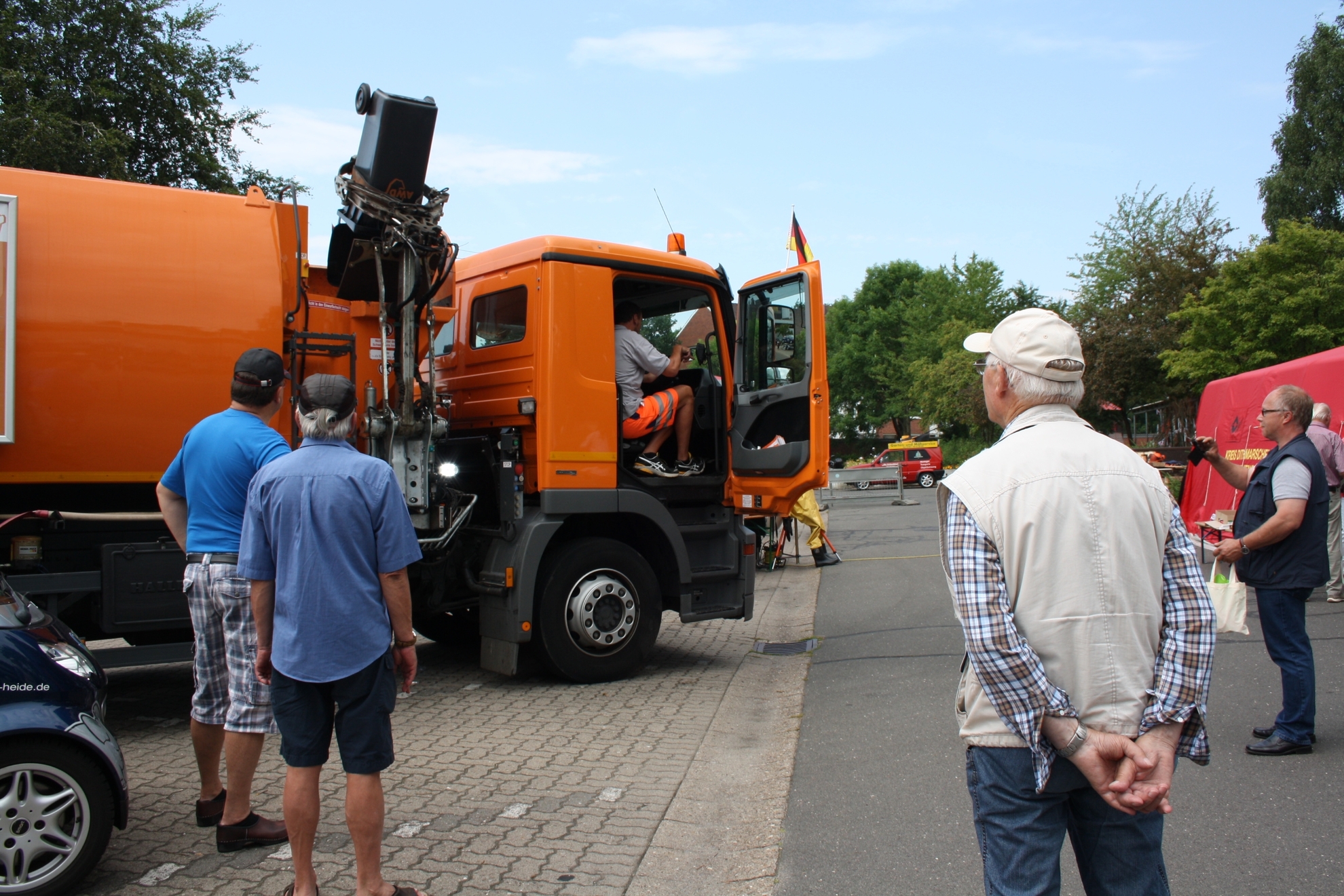 Menschen bestaunen ein Müllfahrzeug.
