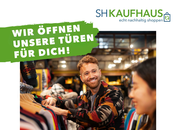 Ein junger Mann schaut sich Secondhand-Kleidung an und lacht.
