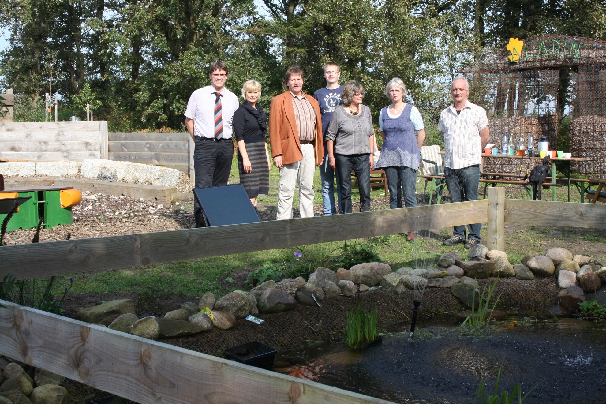 ALADIN Garten mit Gruppe der Initiatoren vor einem Teich.