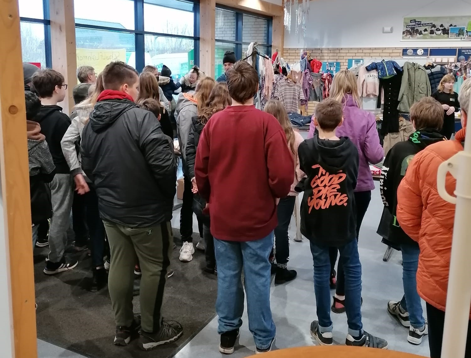 Schülergruppe im Foyer schaut interessiert auf die Präsentationen an den Messeständen.