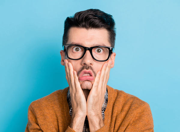 Mann mit Brille blickt verzweifelt in die Kamera und hält die Hände an die Wangen.