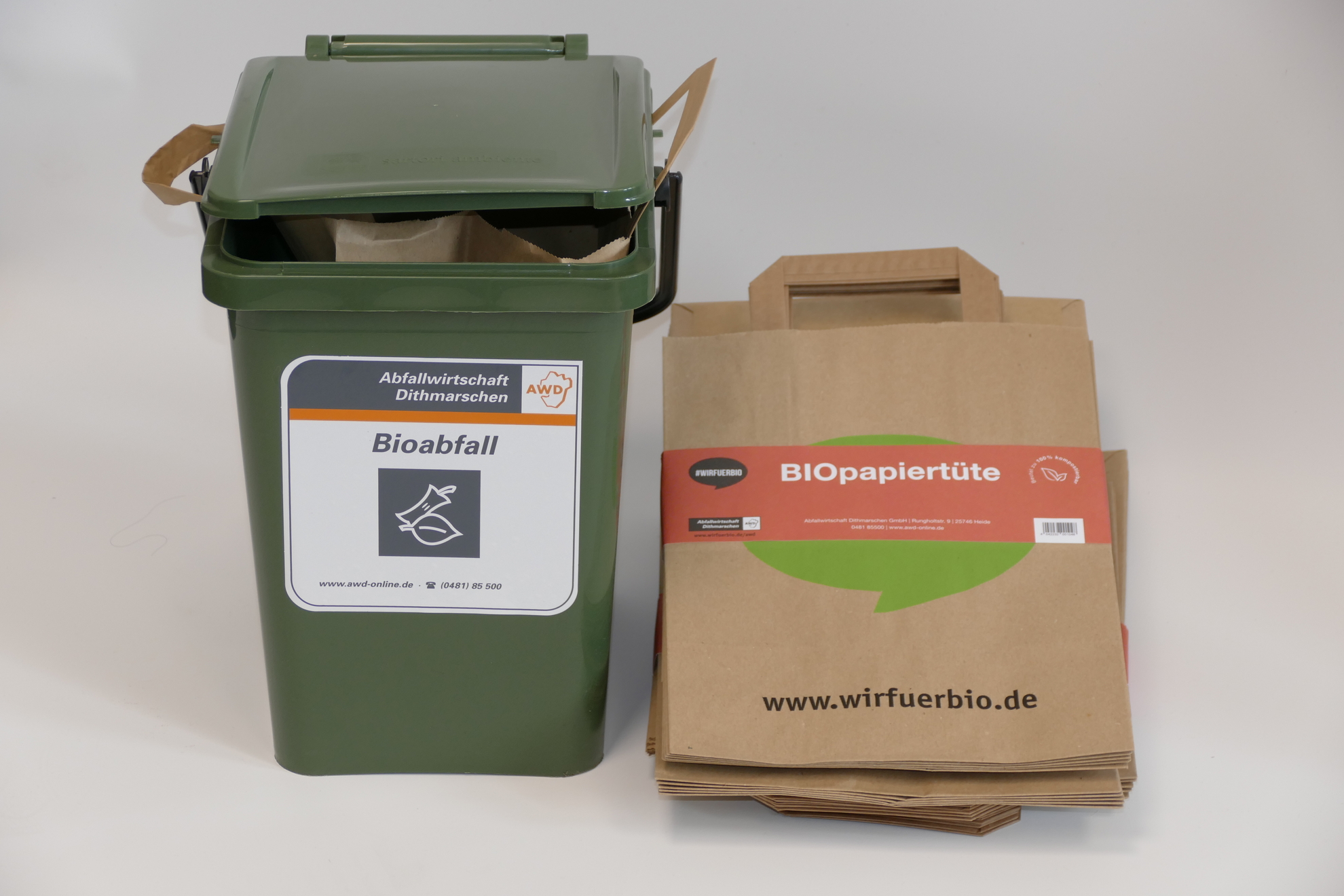 Grünes Bio-Vorsortiergefäß mit Paket von Biopapiertüten.