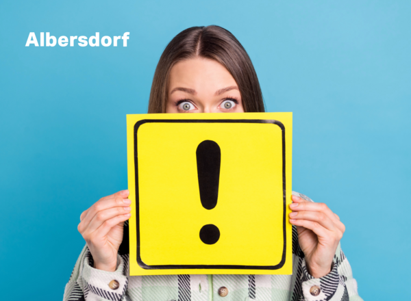 Frau hält gelbes Schild mit einem Achtungzeichen in Händen