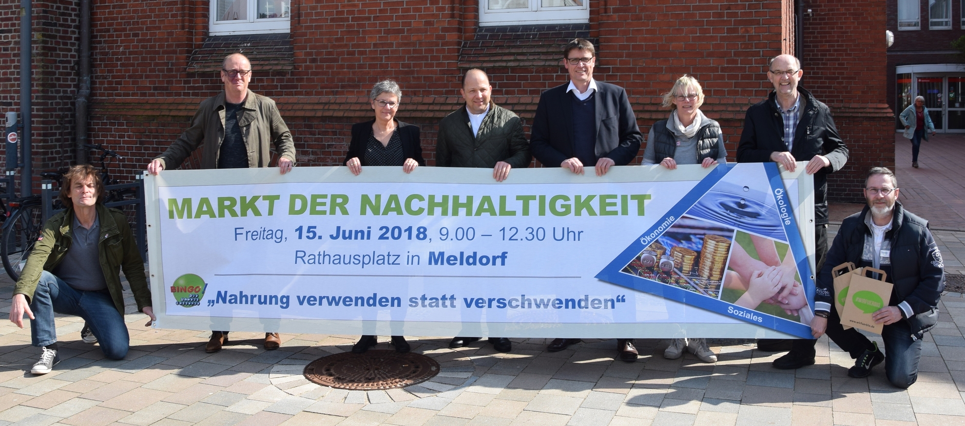 Initiatoren halten Plakat "Markt der Nachhaltigkeit" hoch.