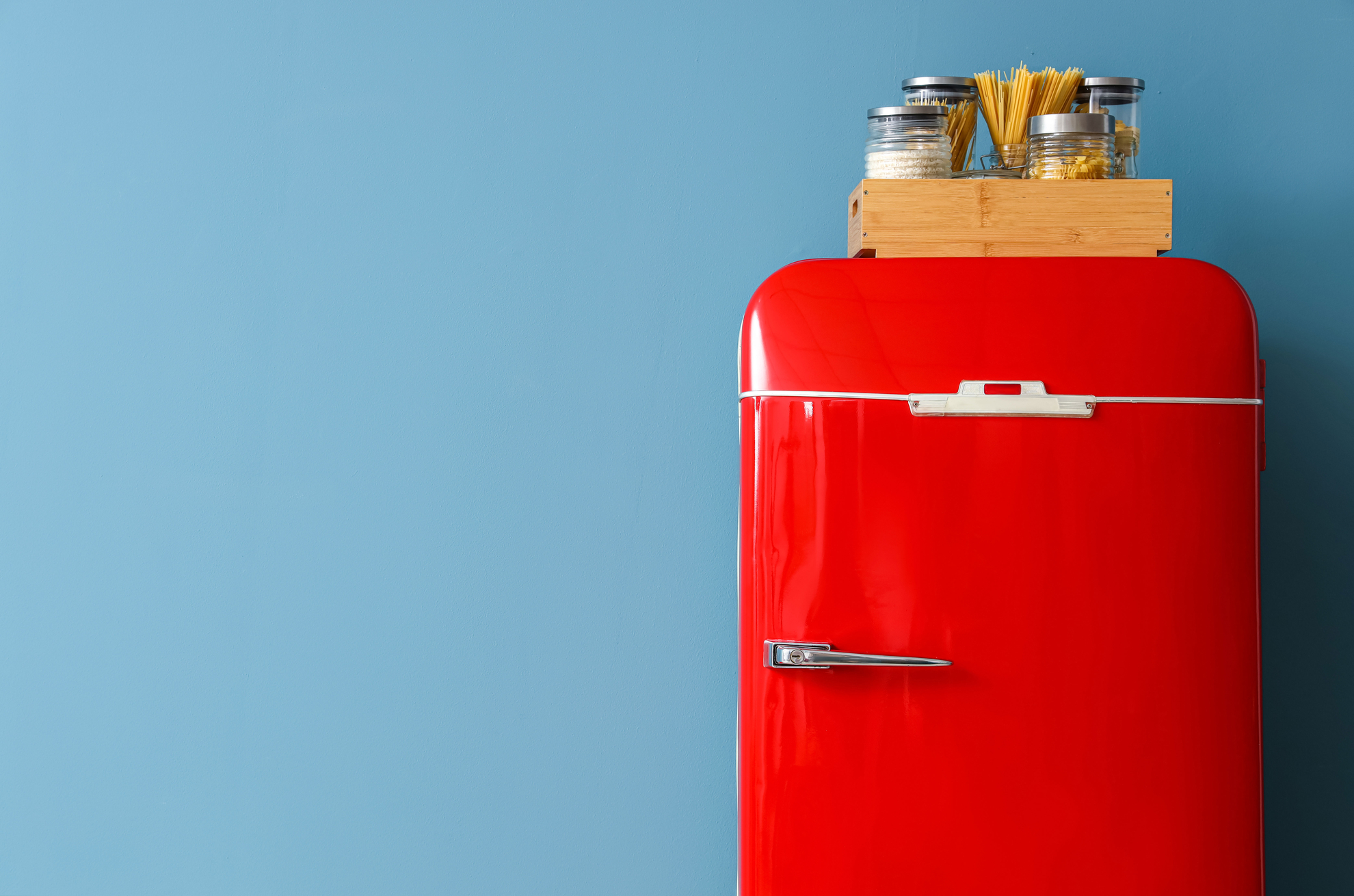 Roter Kühlschrank Roter Kühlschrank in Küche, auf dem Vorräte wie Nudeln und Salz in einer Holzbox stehen.